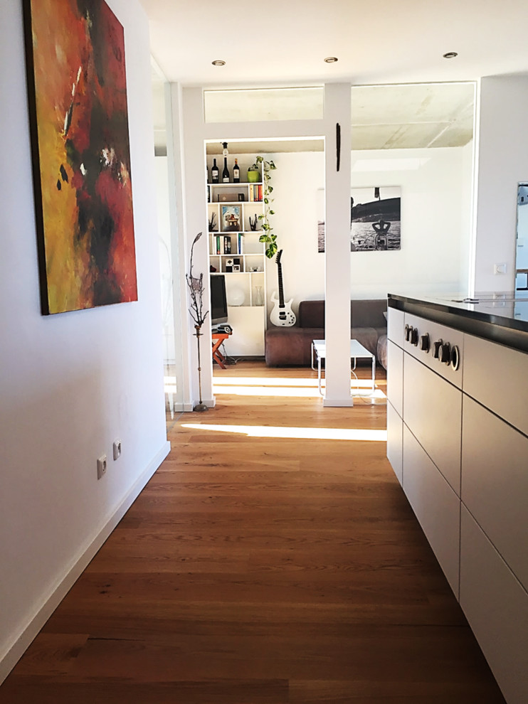 Mittelgroßes Modernes Arbeitszimmer mit weißer Wandfarbe, braunem Holzboden und braunem Boden in München