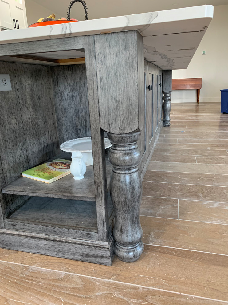 Inspiration for a large rustic l-shaped brown floor open concept kitchen remodel with an undermount sink, recessed-panel cabinets, white cabinets, quartz countertops, white backsplash, stainless steel appliances, an island and white countertops