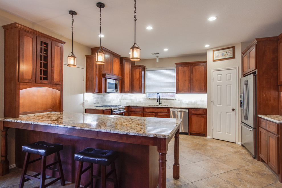 Inspiration for a large traditional u-shaped eat-in kitchen in Dallas with an undermount sink, shaker cabinets, medium wood cabinets, granite benchtops, beige splashback, stone tile splashback, stainless steel appliances, porcelain floors and with island.