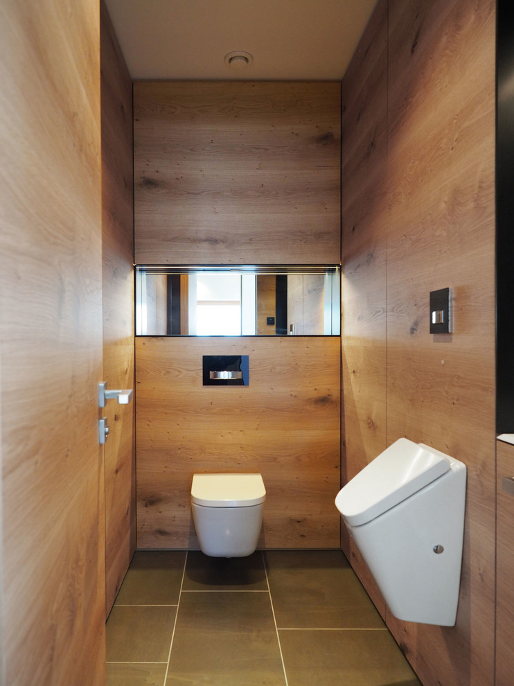 Design ideas for a small contemporary powder room in Nuremberg with a wall-mount toilet, light wood cabinets, marble floors and a drop-in sink.