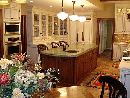 This is an example of a mid-sized traditional u-shaped eat-in kitchen in New York with an undermount sink, raised-panel cabinets, white cabinets, granite benchtops, beige splashback, ceramic splashback, stainless steel appliances, brick floors, with island and brown floor.