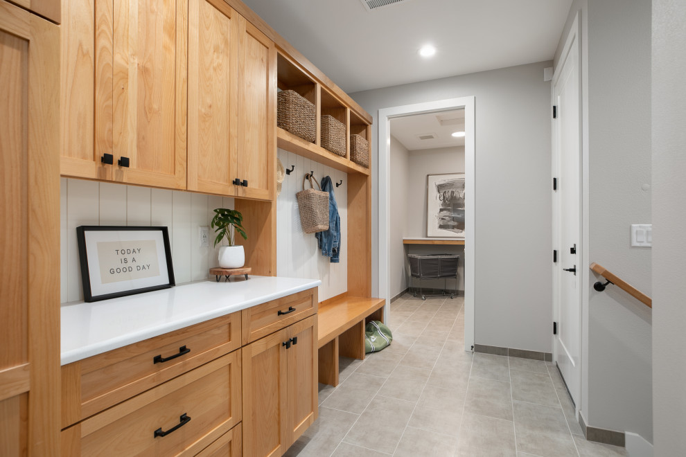 Design ideas for a mid-sized modern galley utility room in Portland with a drop-in sink, shaker cabinets, brown cabinets, quartz benchtops, white splashback, white walls, porcelain floors, a concealed washer and dryer, grey floor and white benchtop.