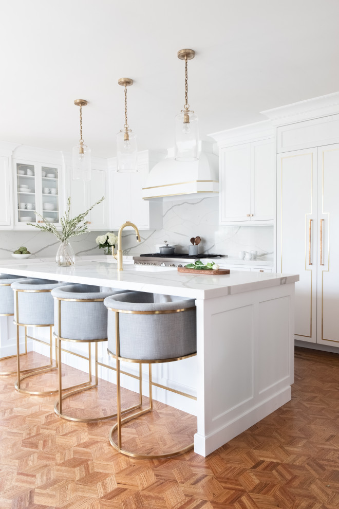 Photo of a large transitional l-shaped kitchen in New York with medium hardwood floors, an undermount sink, shaker cabinets, white cabinets, white splashback, panelled appliances, with island, beige floor and white benchtop.