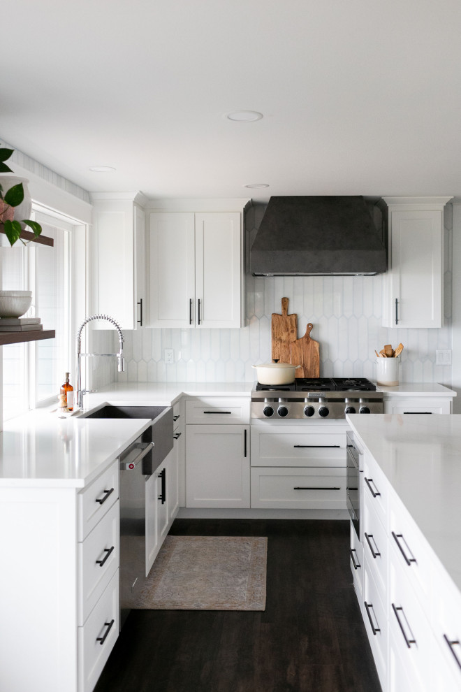 Design ideas for a large transitional l-shaped kitchen in Portland with a farmhouse sink, shaker cabinets, white cabinets, quartzite benchtops, white splashback, stainless steel appliances, laminate floors, with island, brown floor and white benchtop.