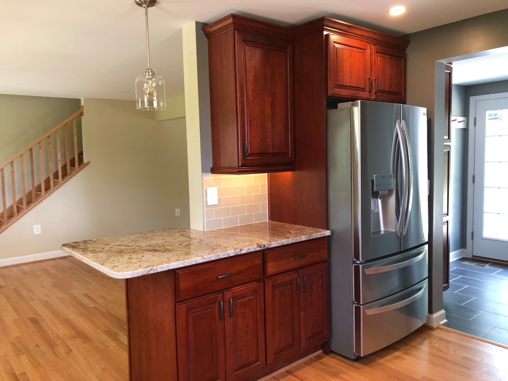 Small traditional l-shaped eat-in kitchen in Baltimore with an undermount sink, raised-panel cabinets, red cabinets, granite benchtops, grey splashback, glass tile splashback, stainless steel appliances, light hardwood floors, a peninsula, brown floor and multi-coloured benchtop.