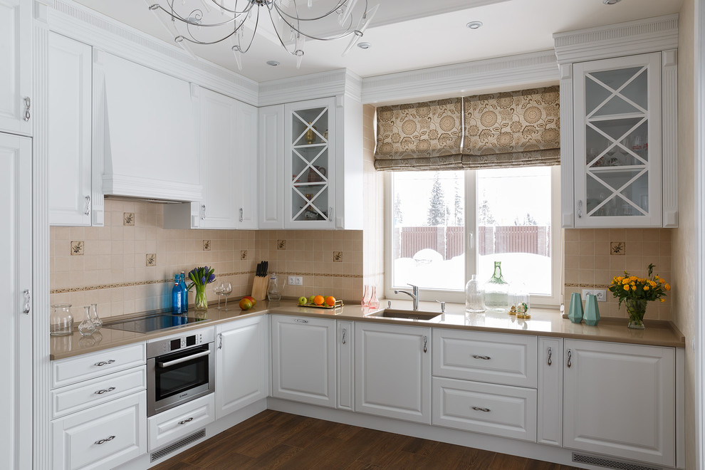 Mid-sized transitional l-shaped separate kitchen in Saint Petersburg with an undermount sink, raised-panel cabinets, white cabinets, beige splashback, stainless steel appliances, no island, brown floor, quartz benchtops, stone tile splashback and brown benchtop.