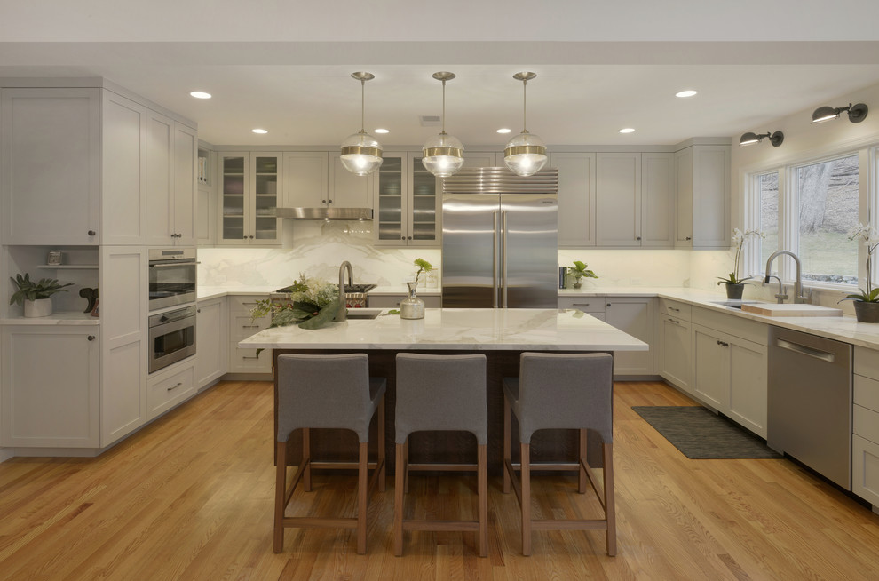 Inspiration for a mid-sized modern u-shaped eat-in kitchen in New York with an undermount sink, shaker cabinets, grey cabinets, tile benchtops, white splashback, porcelain splashback, stainless steel appliances, light hardwood floors, with island and brown floor.