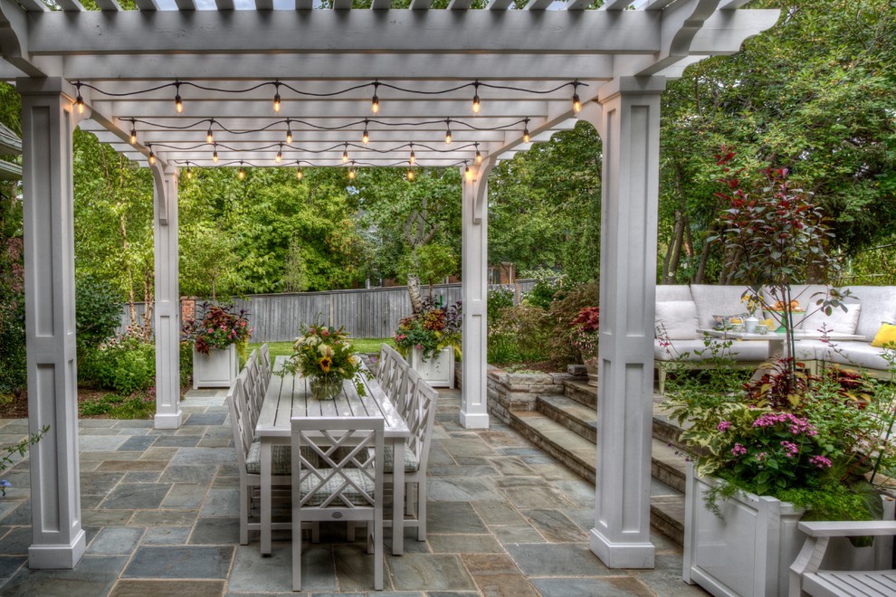 Photo of a traditional patio in Denver with natural stone pavers and a pergola.