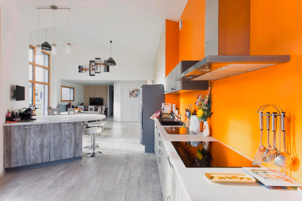This is an example of a large country single-wall open plan kitchen in Clermont-Ferrand with light wood cabinets, light hardwood floors, grey floor and white benchtop.