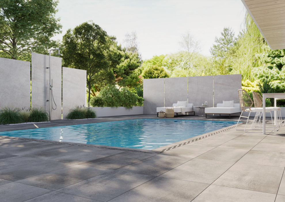 На фото: прямоугольный бассейн-инфинити среднего размера на заднем дворе в современном стиле с перегородкой для приватности и покрытием из плитки