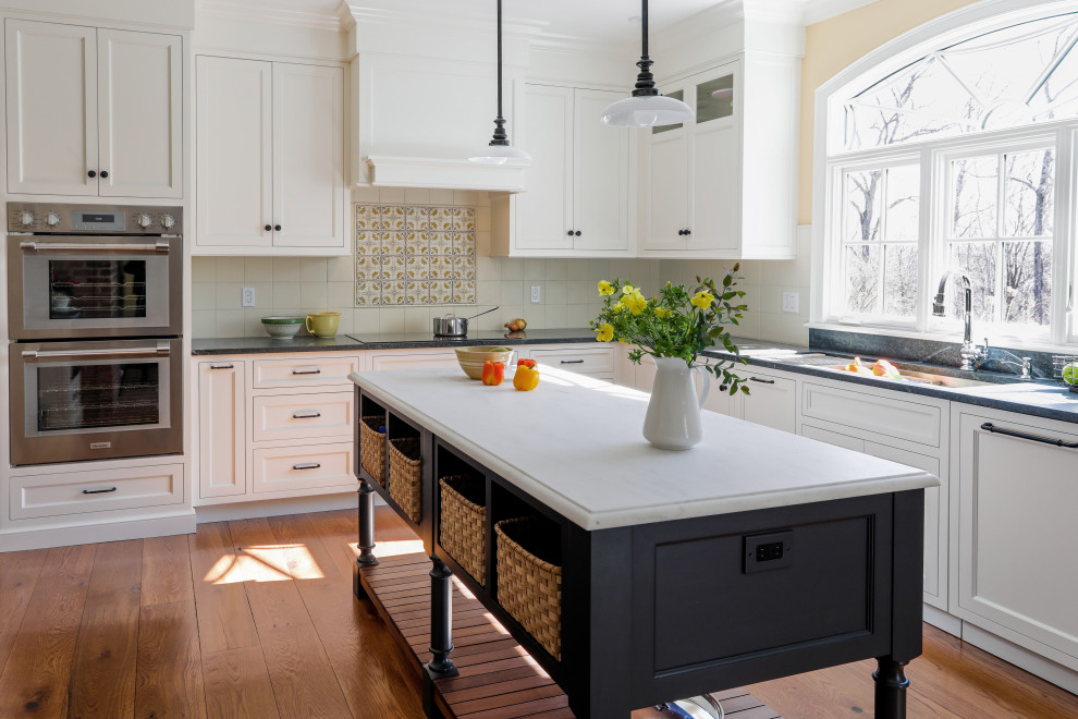 Inspiration for a large rural l-shaped kitchen/diner in New York with a single-bowl sink, flat-panel cabinets, white cabinets, marble worktops, yellow splashback, cement tile splashback, white appliances, dark hardwood flooring, an island, brown floors and white worktops.