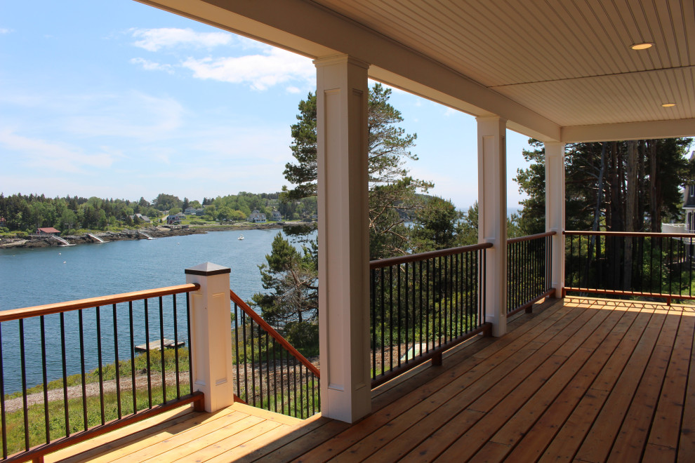Photo of a large nautical back mixed railing veranda in Portland Maine with with columns and a roof extension.