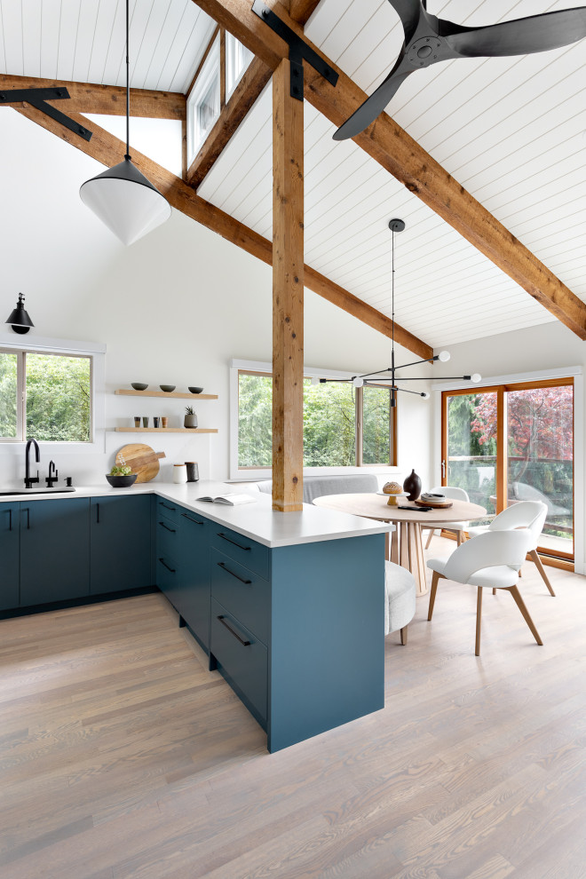 Design ideas for a mid-sized midcentury l-shaped eat-in kitchen in Vancouver with an undermount sink, flat-panel cabinets, blue cabinets, quartz benchtops, white splashback, engineered quartz splashback, stainless steel appliances, light hardwood floors, a peninsula, beige floor, white benchtop and exposed beam.