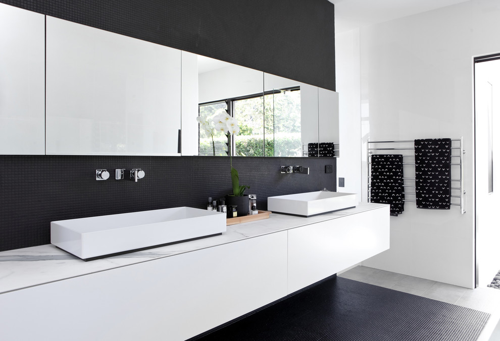 Design ideas for a contemporary master bathroom in Sunshine Coast with flat-panel cabinets, white cabinets, black tile, mosaic tile, white walls, mosaic tile floors, a vessel sink, black floor and white benchtops.