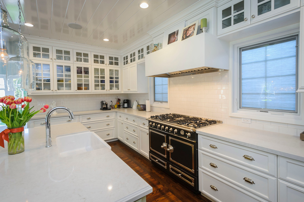 Photo of a large country u-shaped eat-in kitchen in San Francisco with a farmhouse sink, shaker cabinets, white cabinets, quartzite benchtops, white splashback, ceramic splashback, stainless steel appliances and medium hardwood floors.