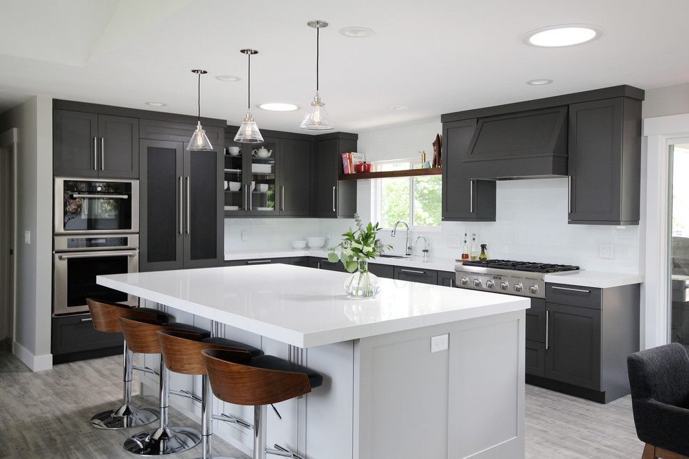 Photo of a transitional l-shaped kitchen in Salt Lake City with shaker cabinets, grey cabinets, white splashback, stainless steel appliances, with island, grey floor and white benchtop.