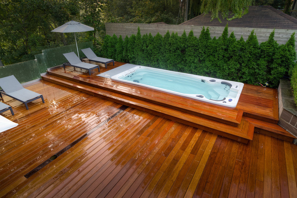 Small modern backyard rectangular lap pool in Toronto with a hot tub and decking.