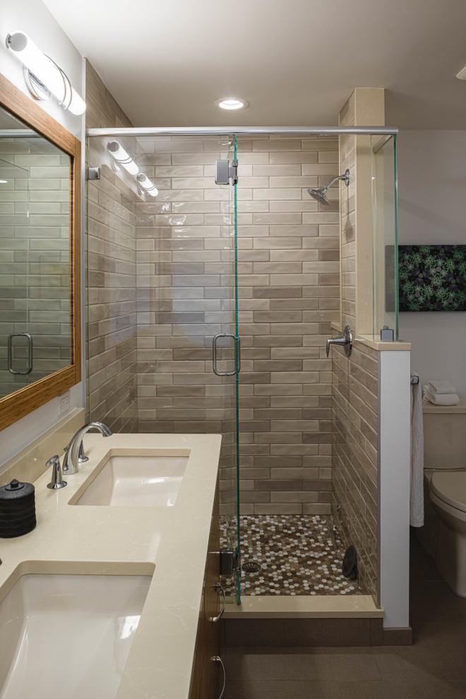 Example of a mid-sized transitional master beige tile and ceramic tile ceramic tile, beige floor and double-sink bathroom design in Detroit with furniture-like cabinets, medium tone wood cabinets, a one-piece toilet, white walls, an undermount sink, solid surface countertops, a hinged shower door, beige countertops and a built-in vanity