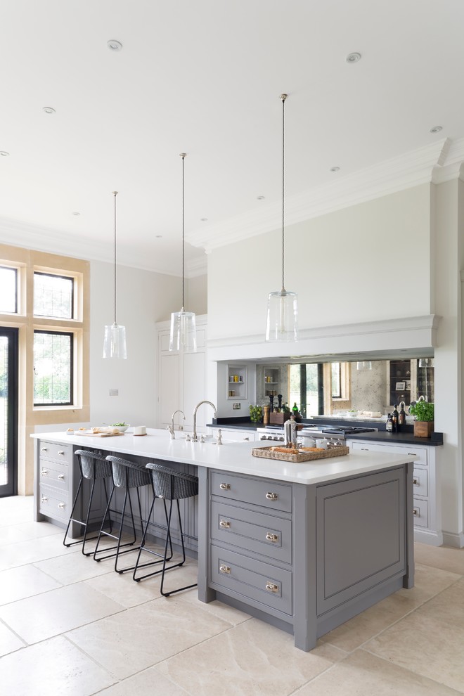 Design ideas for a large transitional galley open plan kitchen in Essex with with island, a double-bowl sink, metallic splashback, mirror splashback, stainless steel appliances and limestone floors.