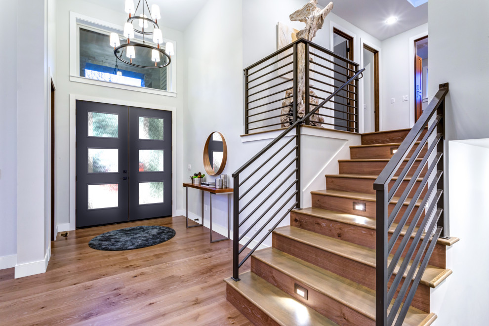 Photo of a large modern foyer in Los Angeles with grey walls, medium hardwood floors, a double front door, a gray front door, brown floor and vaulted.