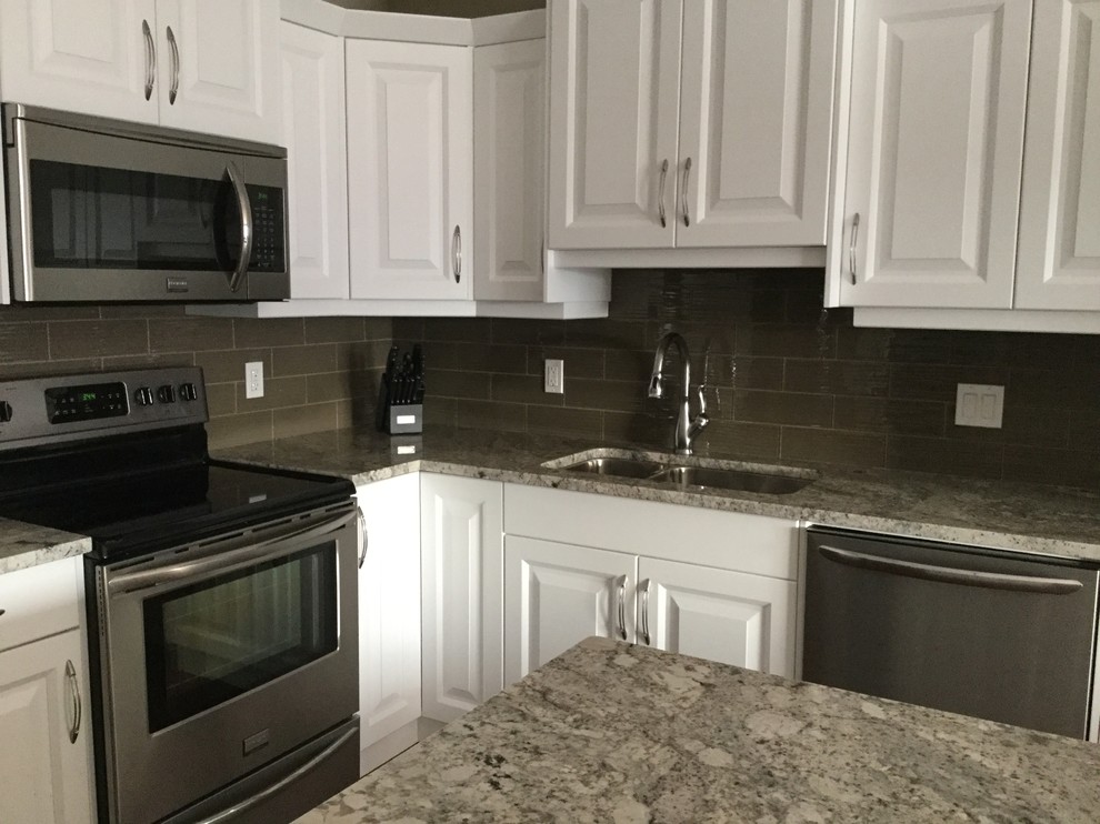 Kitchen - mid-sized traditional kitchen idea with a double-bowl sink, raised-panel cabinets, white cabinets, granite countertops, stainless steel appliances, an island, brown backsplash and glass tile backsplash