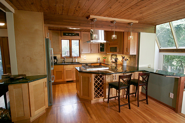 Example of a small transitional l-shaped porcelain tile eat-in kitchen design with shaker cabinets, light wood cabinets, granite countertops, beige backsplash, glass tile backsplash, stainless steel appliances and a peninsula