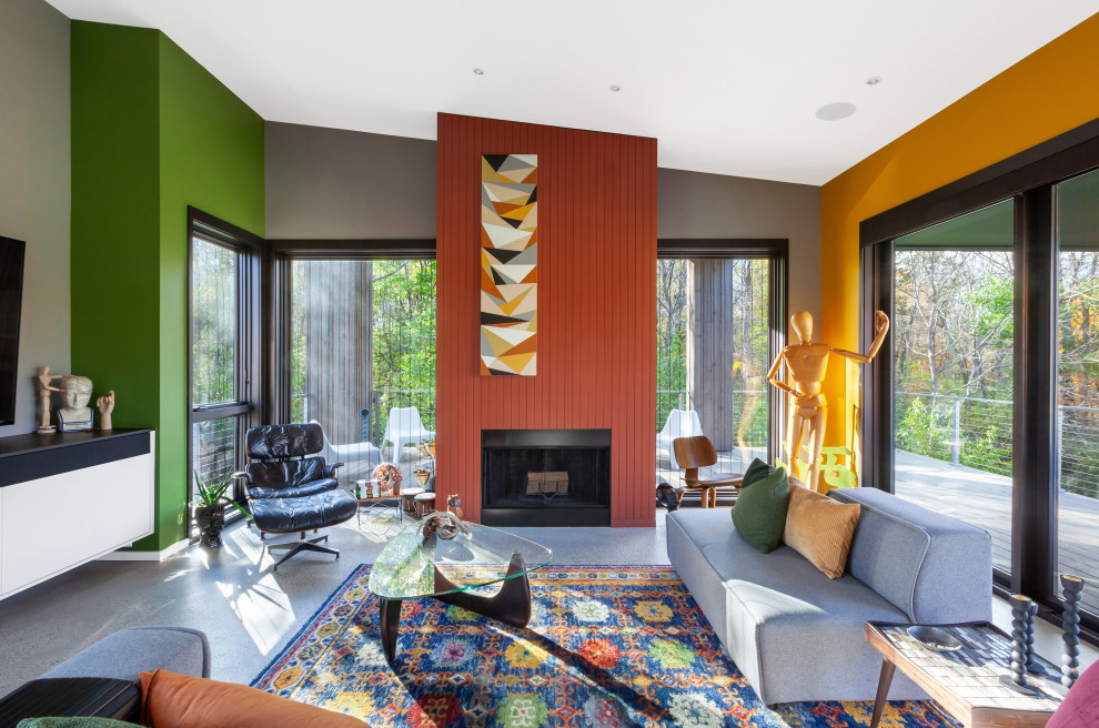 На фото: открытая гостиная комната среднего размера в стиле ретро с желтыми стенами, бетонным полом, стандартным камином, фасадом камина из дерева, телевизором на стене, серым полом, сводчатым потолком и ковром на полу