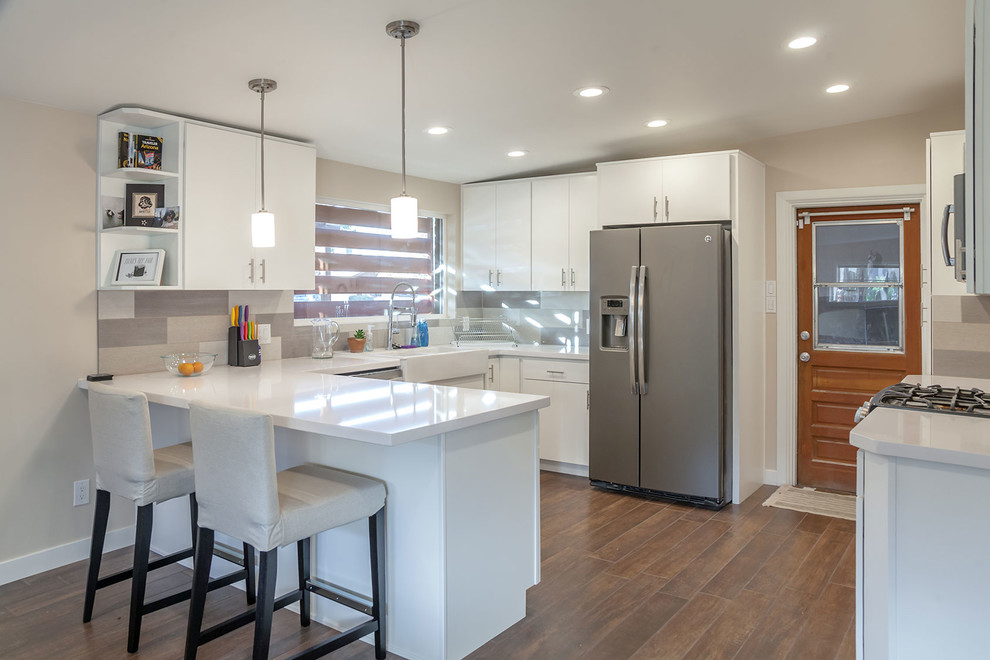 Open concept kitchen - transitional u-shaped porcelain tile open concept kitchen idea in Phoenix with a farmhouse sink, shaker cabinets, white cabinets, quartz countertops, multicolored backsplash, porcelain backsplash, stainless steel appliances and an island