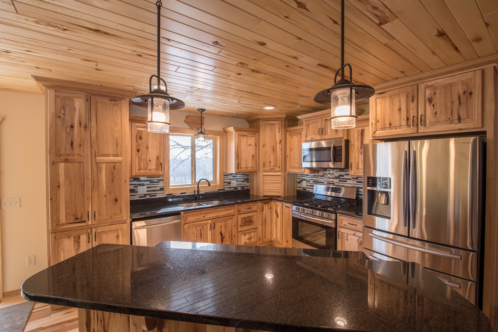 Inspiration for a mid-sized rustic l-shaped light wood floor open concept kitchen remodel in Minneapolis with a double-bowl sink, raised-panel cabinets, light wood cabinets, granite countertops, multicolored backsplash, matchstick tile backsplash, stainless steel appliances and an island