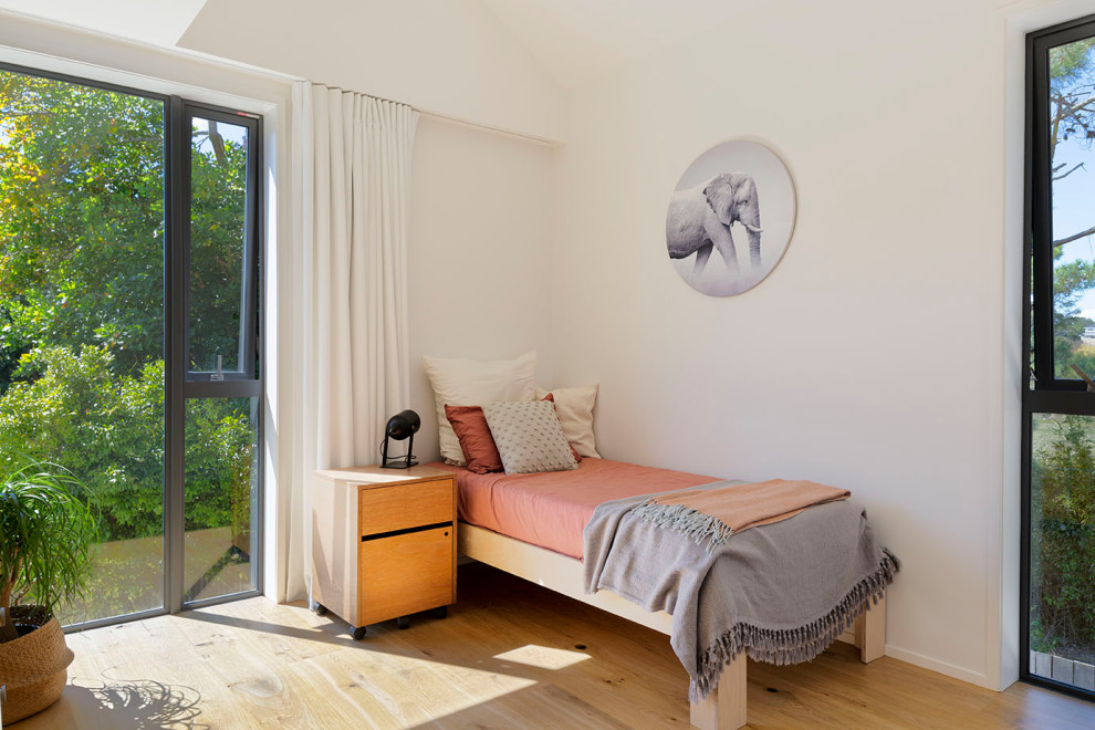 Mid-sized contemporary bedroom in Auckland with white walls, medium hardwood floors, grey floor and vaulted.