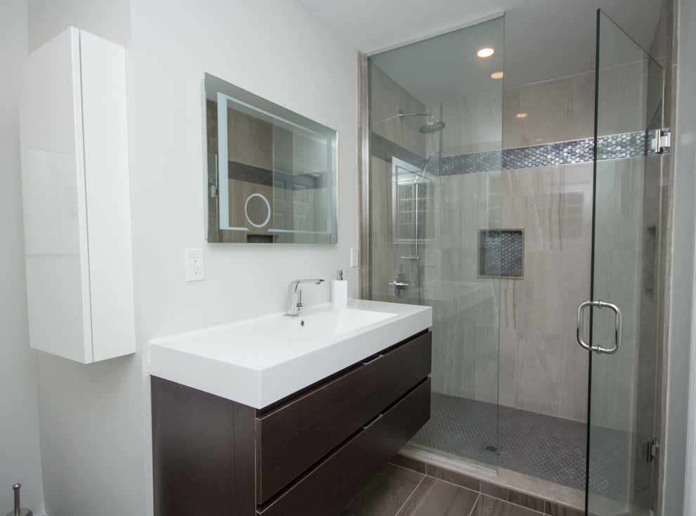 Design ideas for a mid-sized contemporary 3/4 bathroom in Toronto with an integrated sink, flat-panel cabinets, dark wood cabinets, solid surface benchtops, an alcove shower, a one-piece toilet, brown tile, pebble tile, grey walls and porcelain floors.