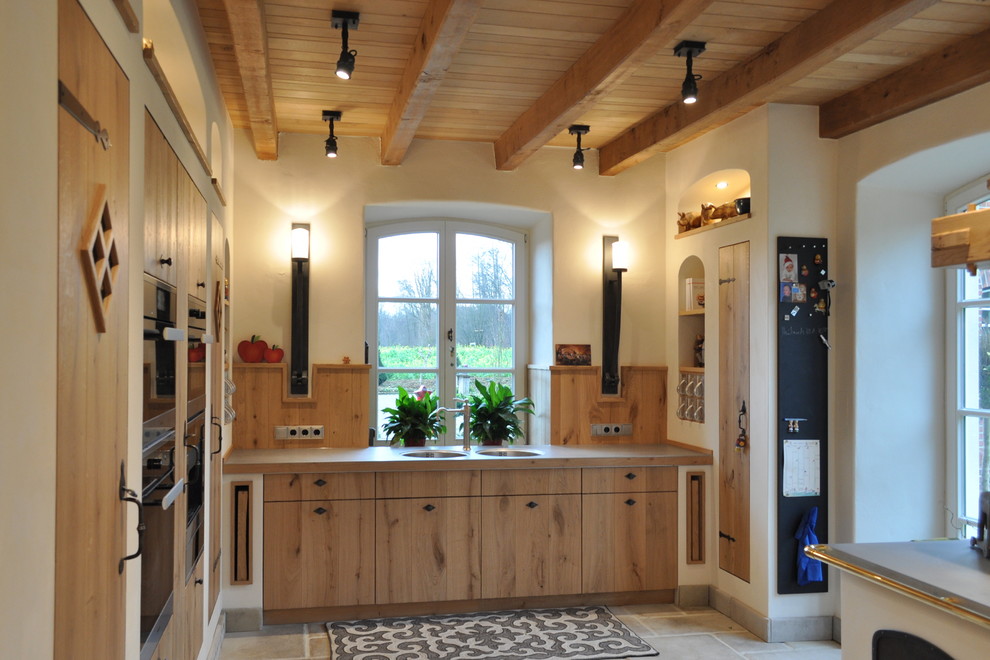 Photo of an expansive country eat-in kitchen in Dortmund with medium wood cabinets, stainless steel benchtops, stainless steel appliances, flat-panel cabinets, a double-bowl sink, no island and timber splashback.