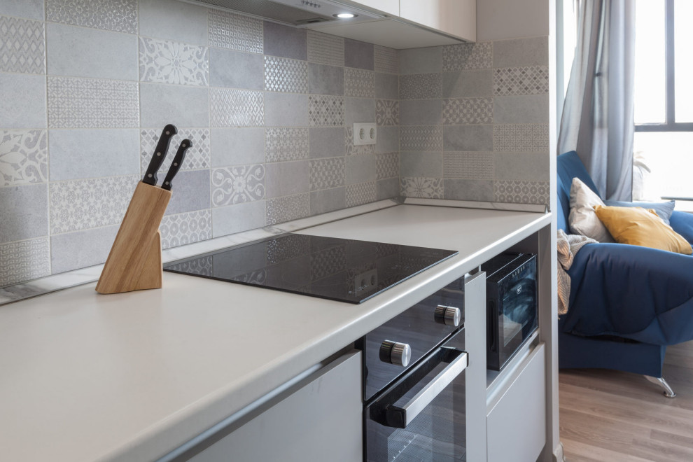 Foto på ett litet funkis vit kök, med en nedsänkt diskho, släta luckor, grå skåp, träbänkskiva, flerfärgad stänkskydd, stänkskydd i porslinskakel, vita vitvaror, laminatgolv och beiget golv