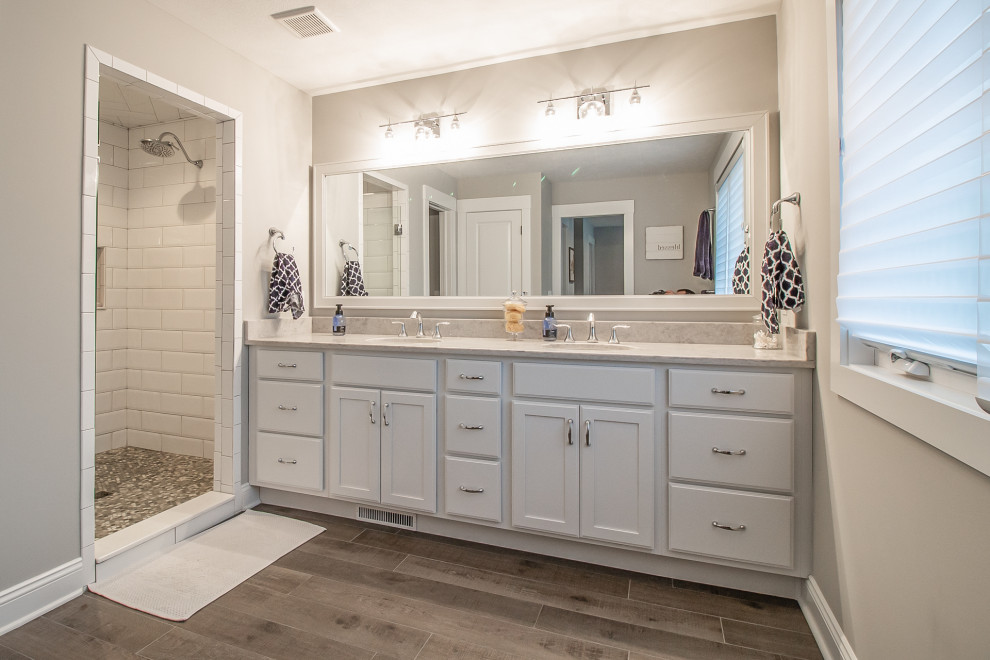 Inspiration for a large traditional master bathroom in Cleveland with recessed-panel cabinets, an alcove shower, white tile, ceramic tile, laminate floors, grey floor, a hinged shower door, multi-coloured benchtops, a double vanity and a built-in vanity.
