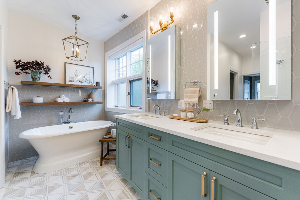 This is an example of a transitional master bathroom in Chicago with shaker cabinets, blue cabinets, a freestanding tub, gray tile, white walls, engineered quartz benchtops, multi-coloured floor, a hinged shower door, white benchtops, a double vanity and a built-in vanity.