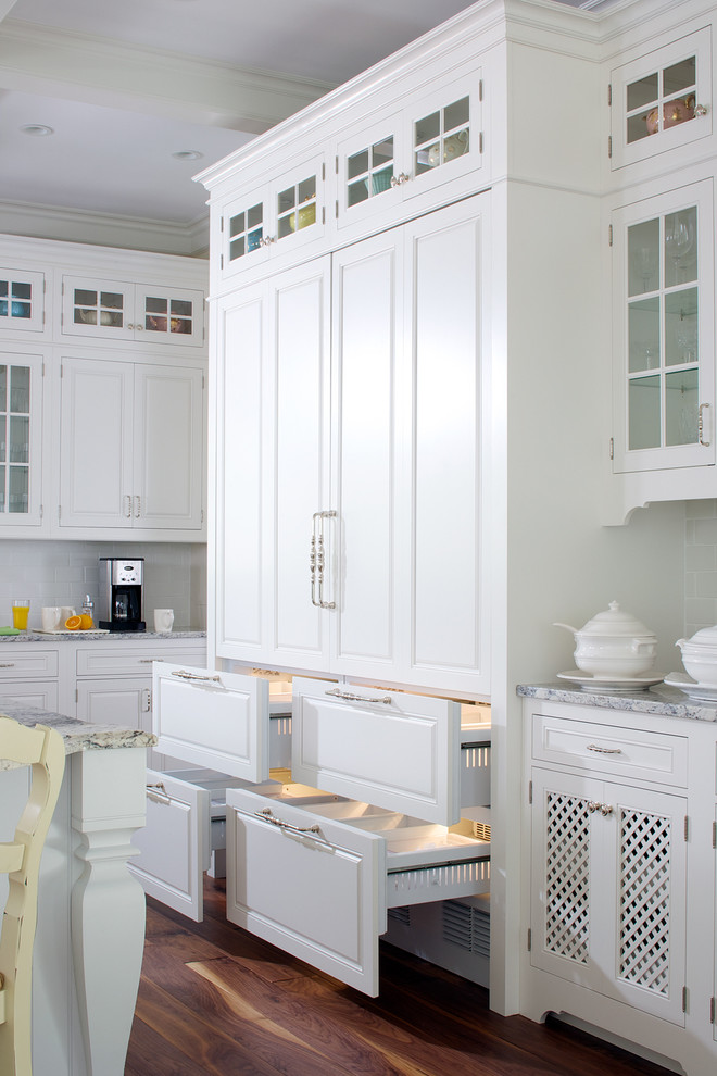 Design ideas for a traditional kitchen in Grand Rapids with raised-panel cabinets, white cabinets, white splashback, subway tile splashback, dark hardwood floors and with island.