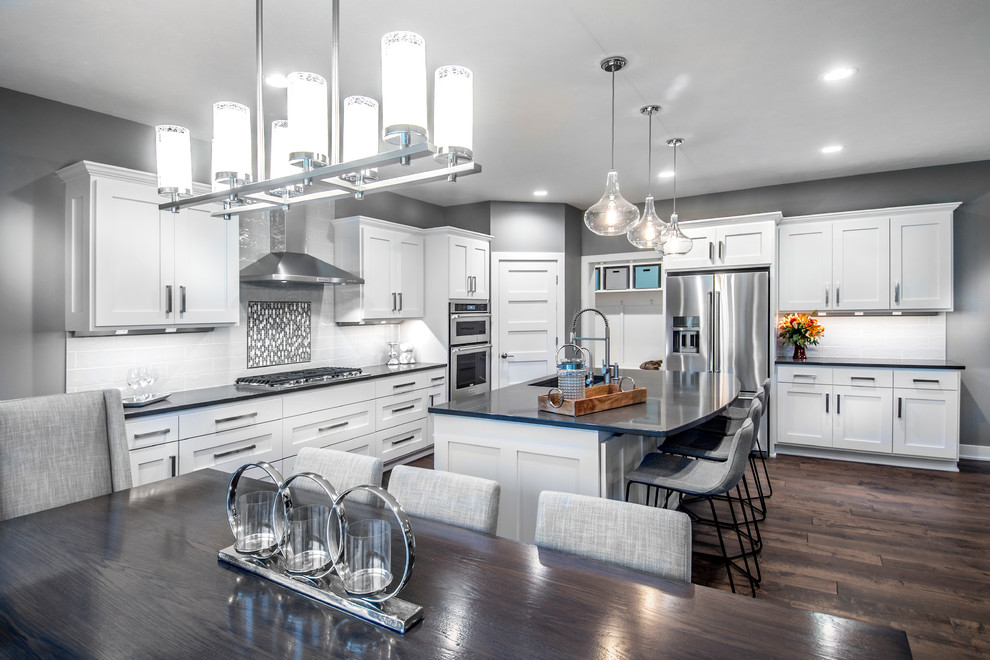 Inspiration for a transitional l-shaped dark wood floor eat-in kitchen remodel with an undermount sink, white cabinets, onyx countertops, subway tile backsplash, stainless steel appliances and an island