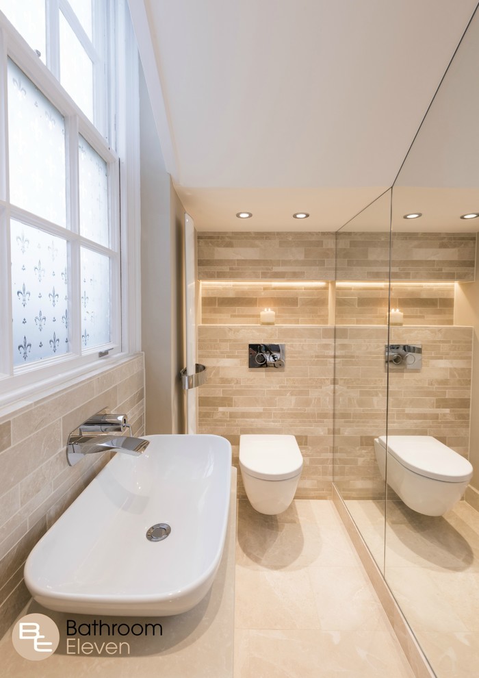This is an example of a small modern bathroom with a wall-mount toilet, beige tile, stone tile, beige walls, ceramic floors, a trough sink and soapstone benchtops.