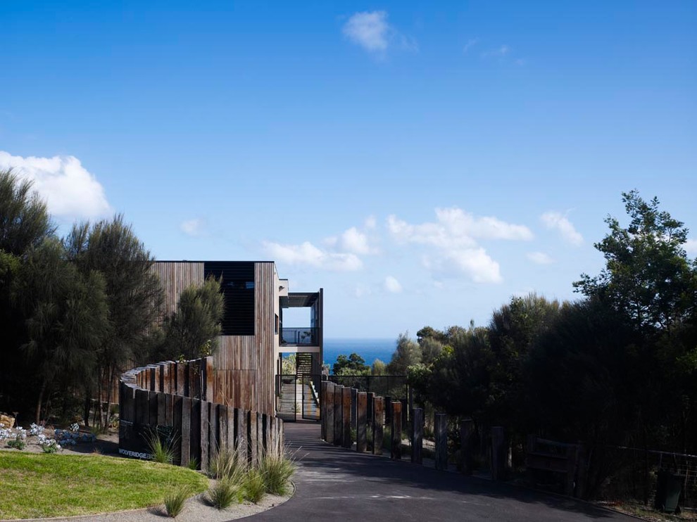 Inspiration for a large beach style two-storey black exterior in Melbourne with wood siding and a flat roof.