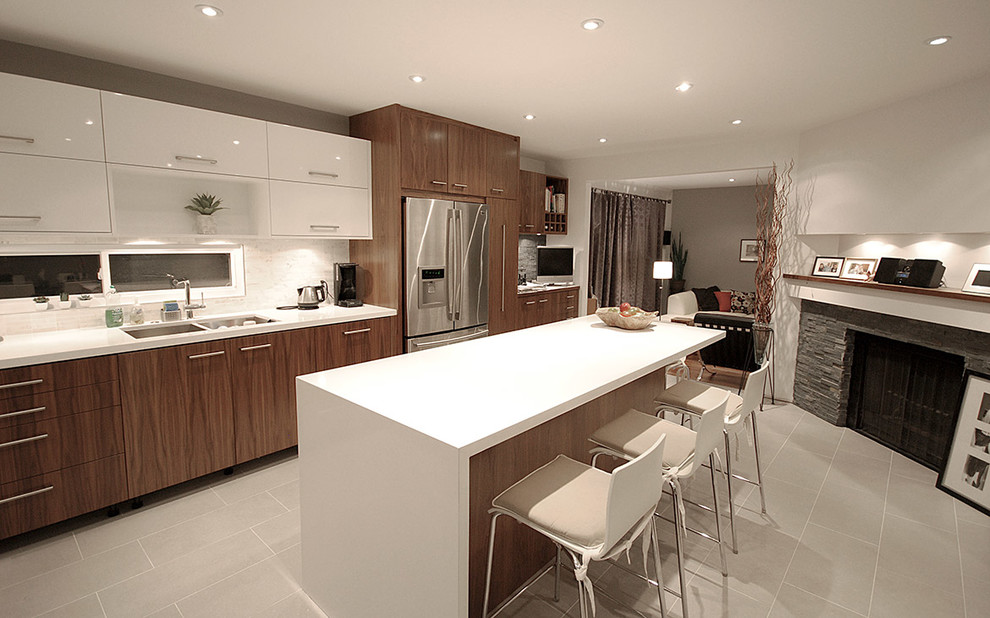 Example of a mid-sized transitional galley ceramic tile eat-in kitchen design in Toronto with a double-bowl sink, flat-panel cabinets, medium tone wood cabinets, solid surface countertops, white backsplash, stone slab backsplash, stainless steel appliances and an island