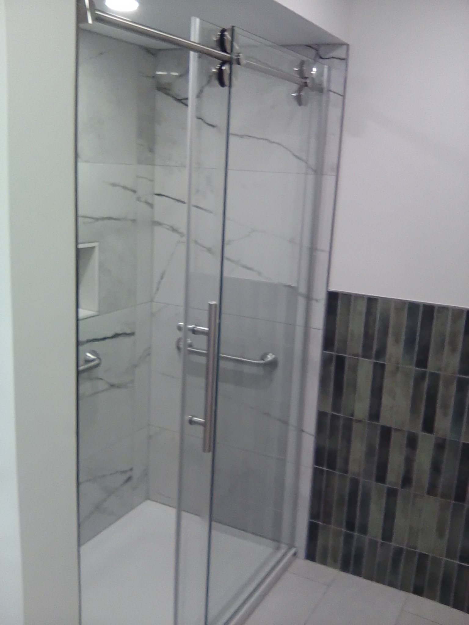 New completed shower, tile, transition to half wall tile, and glass doors