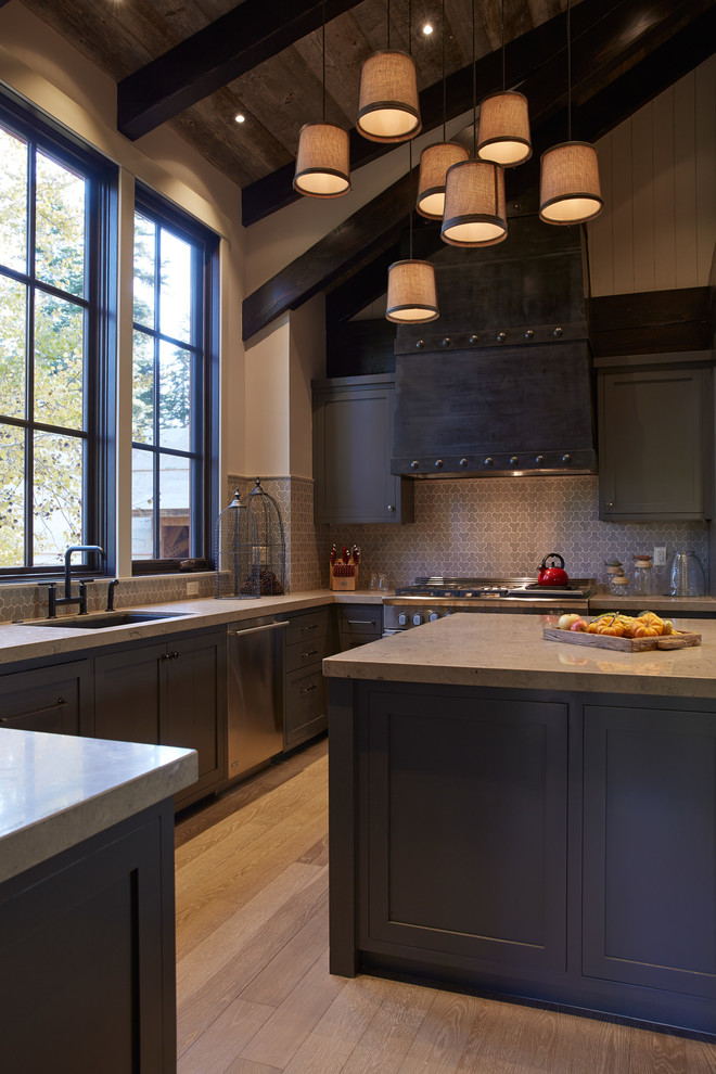 Country kitchen in San Francisco with an undermount sink, shaker cabinets, dark wood cabinets, stainless steel appliances, medium hardwood floors, with island and mosaic tile splashback.