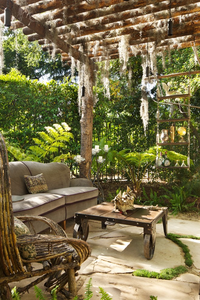 This is an example of an eclectic patio in Los Angeles with a gazebo/cabana and a water feature.