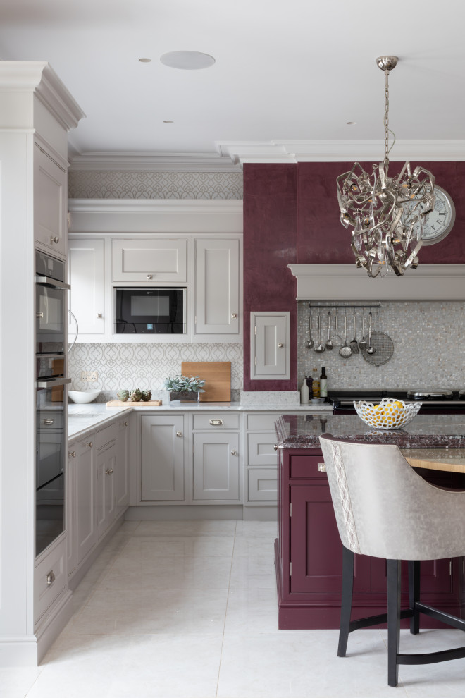 This is an example of an expansive traditional grey and purple u-shaped kitchen/diner in Surrey with a built-in sink, all styles of cabinet, purple cabinets, marble worktops, beige splashback, mosaic tiled splashback, black appliances, ceramic flooring, an island, beige floors, purple worktops and a chimney breast.