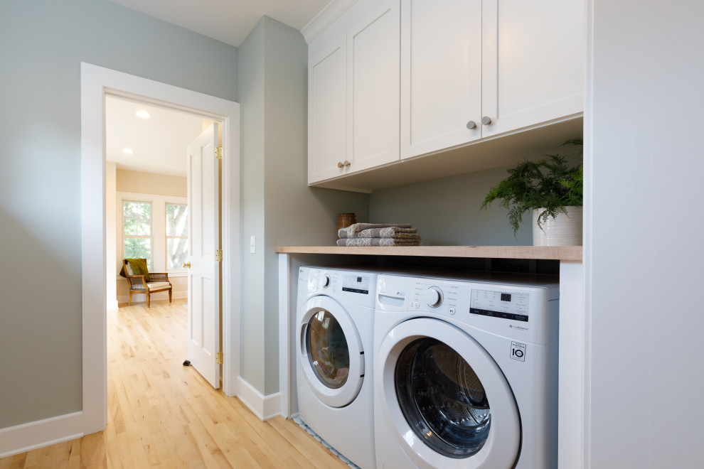 Design ideas for a small transitional single-wall laundry room in Minneapolis with recessed-panel cabinets, white cabinets, laminate benchtops, grey walls, light hardwood floors, a side-by-side washer and dryer and beige benchtop.