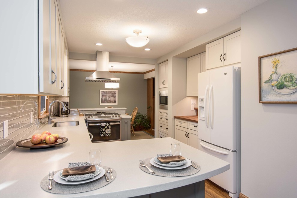 Eat-in kitchen - small transitional galley vinyl floor eat-in kitchen idea with recessed-panel cabinets, white cabinets, gray backsplash and stainless steel appliances