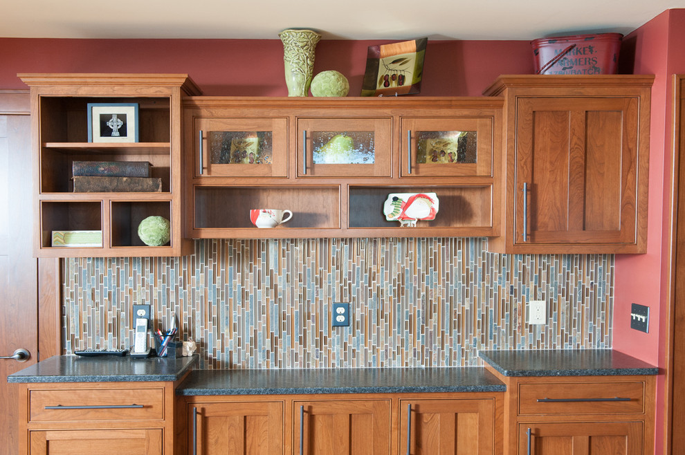 Inspiration for a mid-sized transitional l-shaped medium tone wood floor eat-in kitchen remodel in Orange County with a farmhouse sink, shaker cabinets, medium tone wood cabinets, granite countertops, multicolored backsplash, matchstick tile backsplash, stainless steel appliances and an island