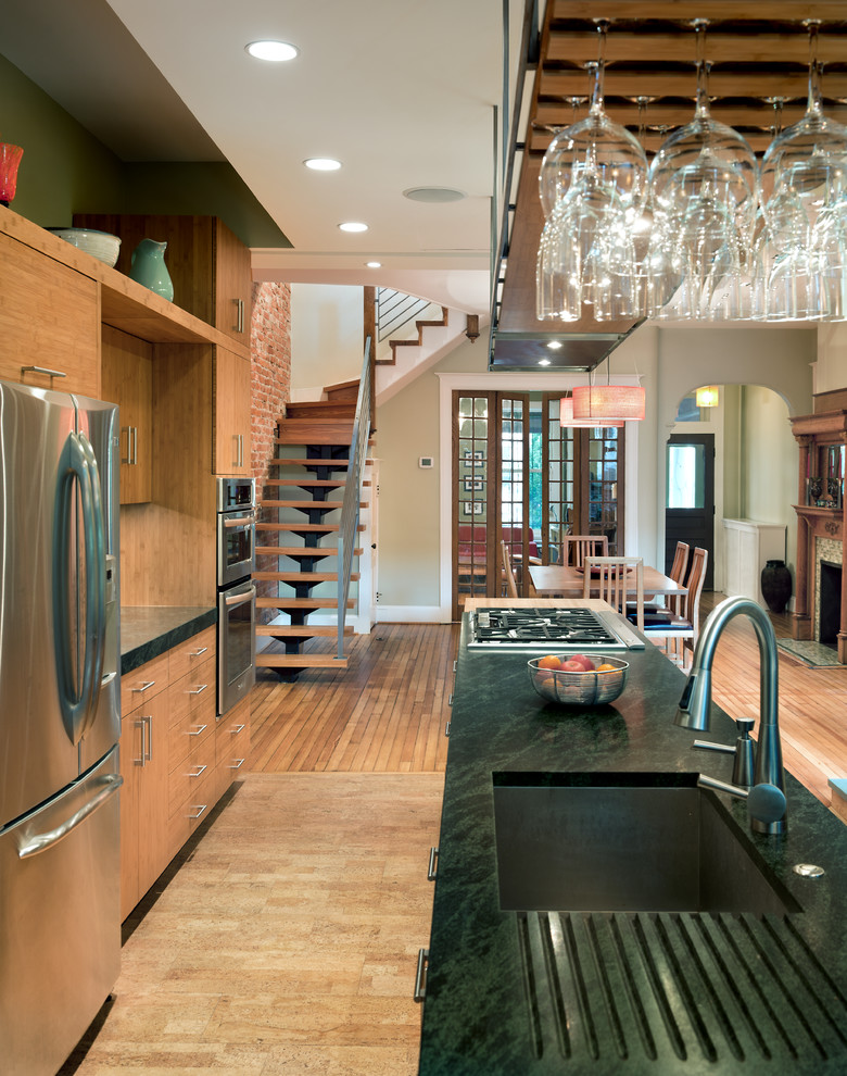 This is an example of a modern galley eat-in kitchen in DC Metro with a single-bowl sink, stainless steel appliances, cork floors and with island.