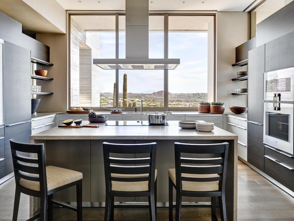 Inspiration for an expansive modern u-shaped kitchen in Phoenix with an undermount sink, flat-panel cabinets, dark wood cabinets, limestone benchtops, stainless steel appliances, medium hardwood floors and with island.