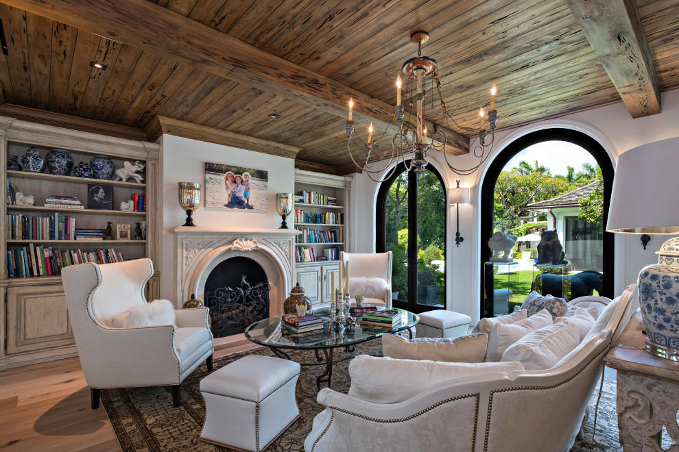 Photo of a large beach style formal enclosed living room in Miami with white walls, light hardwood floors, a standard fireplace, no tv and vaulted.